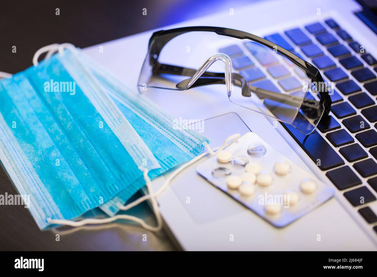 Masques de protection jetables, lunettes, médicaments anti-immuns enveloppés dans du papier aluminium, télétravail à la maison - photo de stock Banque D'Images