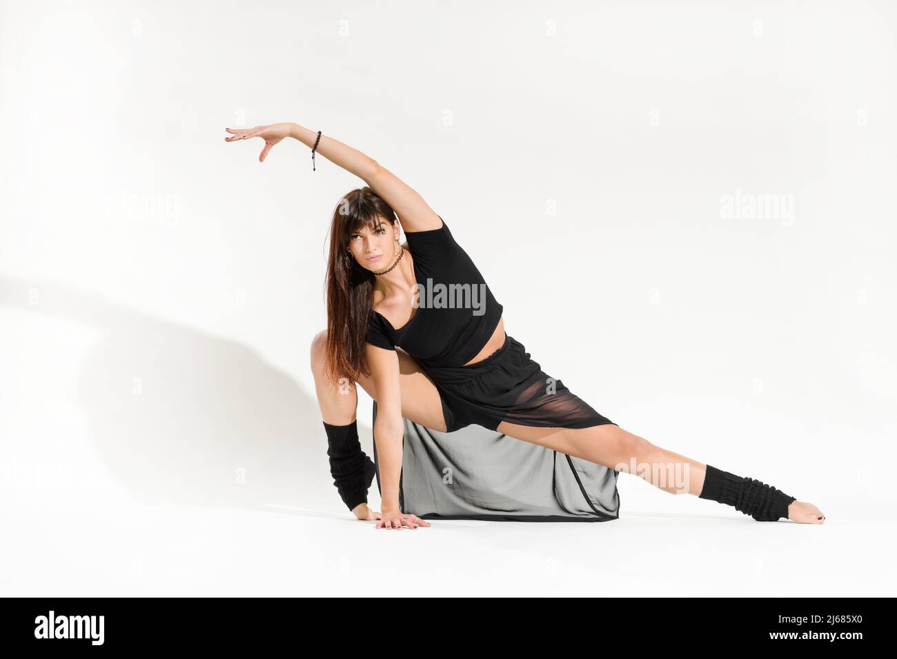 Ensemble de jeunes danseuses en costume noir, extensible sur le devant avec un pas en flexion et un bras relevé sur fond blanc Banque D'Images