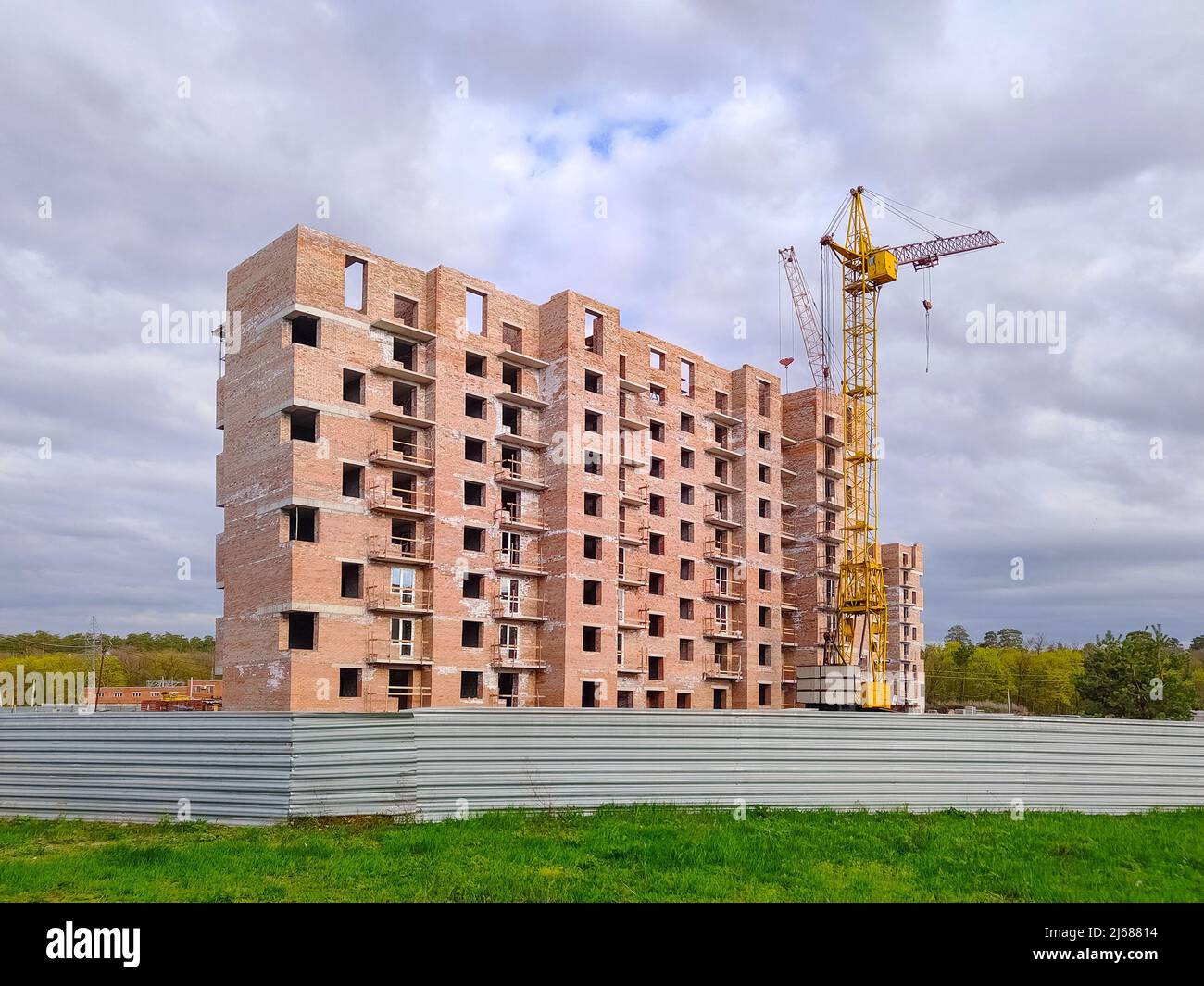 Maison résidentielle en brique en construction. Grue de maison et tour non finie. Nouveau bâtiment à plusieurs étages. Banque D'Images