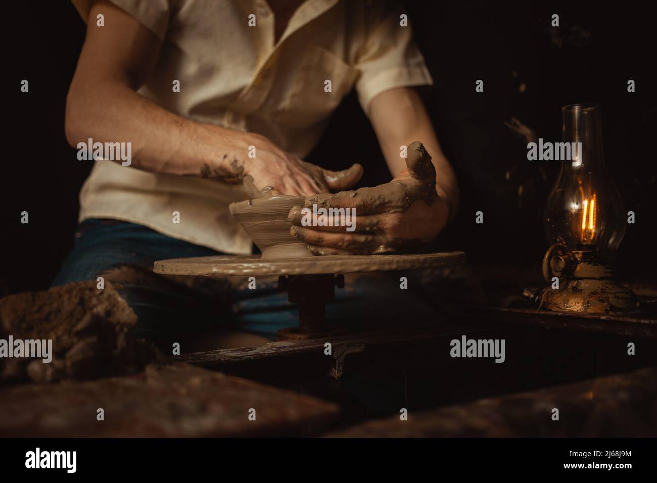 homme dans atelier de poterie fait plaque d'argile, une atmosphère authentique, lampe jaune, style de vie, atmosphère magique. Concept avec vos propres mains, maison fr Banque D'Images