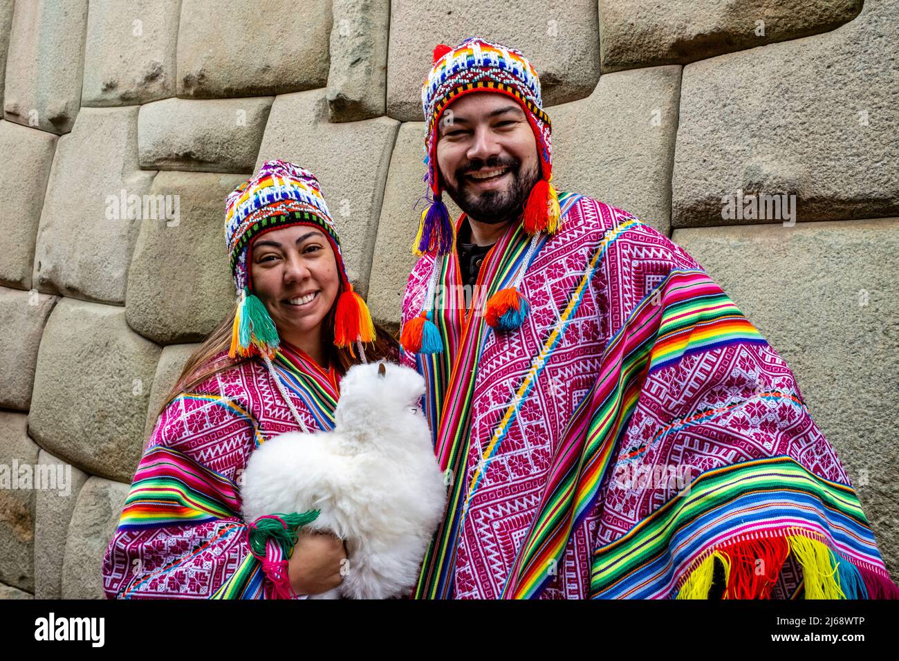 Toursts/visiteurs vêtus de couleur péruvienne Costume pose pour Une photo par le mur Inca, Cusco, province de Cusco, Pérou. Banque D'Images