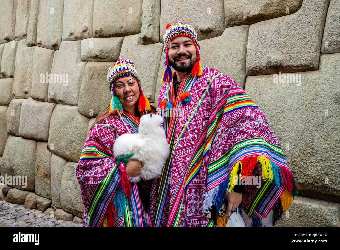 Toursts/visiteurs vêtus de couleur péruvienne Costume pose pour Une photo par le mur Inca, Cusco, province de Cusco, Pérou. Banque D'Images