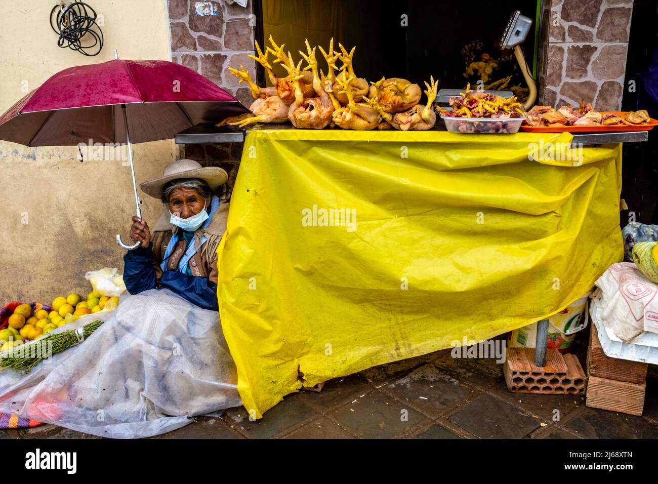 Une femme âgée s'est mise à l'abri de la pluie dans Un marché de rue de Cusco, Cusco, province de Cusco, Pérou. Banque D'Images