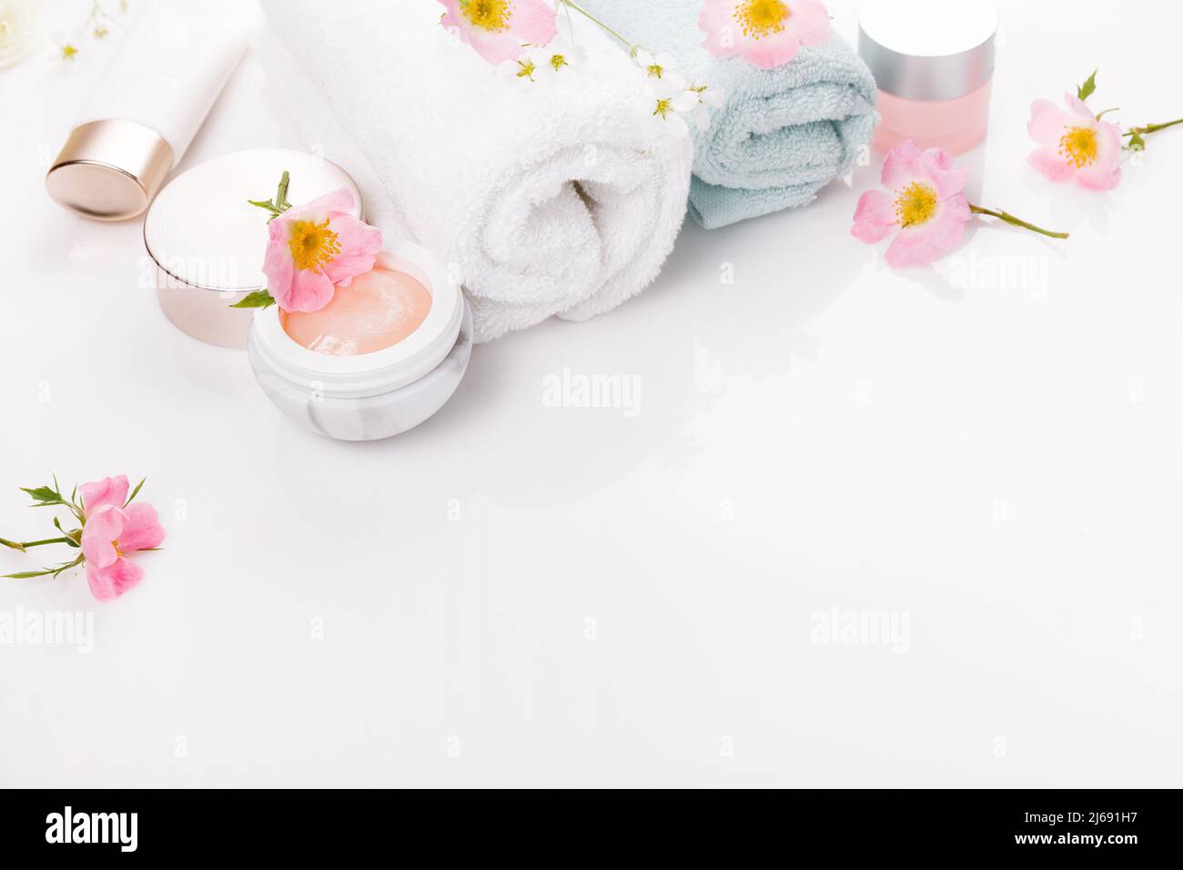 Concept beauté et spa. Serviette et cosmétiques de soin de la peau avec des hanches roses sur fond blanc. Pose à plat. Banque D'Images