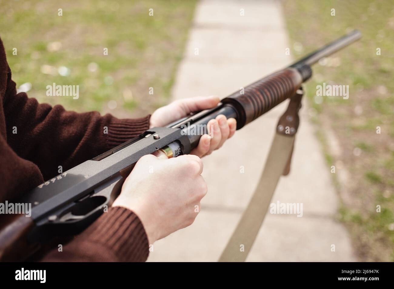 Un jeune homme charge un fusil à pompe avec un Ammo. calibre 12. Pneu extérieur. Un homme dans un casque et des lunettes se prépare à tirer. Armes à feu pour s Banque D'Images