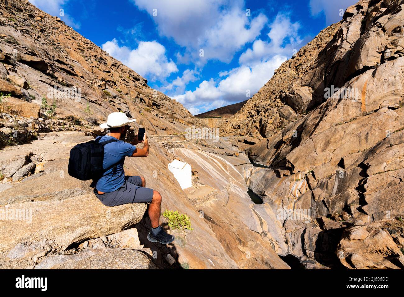 Tourisme photographier des canyons avec un smartphone assis sur des rochers à Barranco de las Penitas, Fuerteventura, îles Canaries, Espagne, Atlantique, Europe Banque D'Images