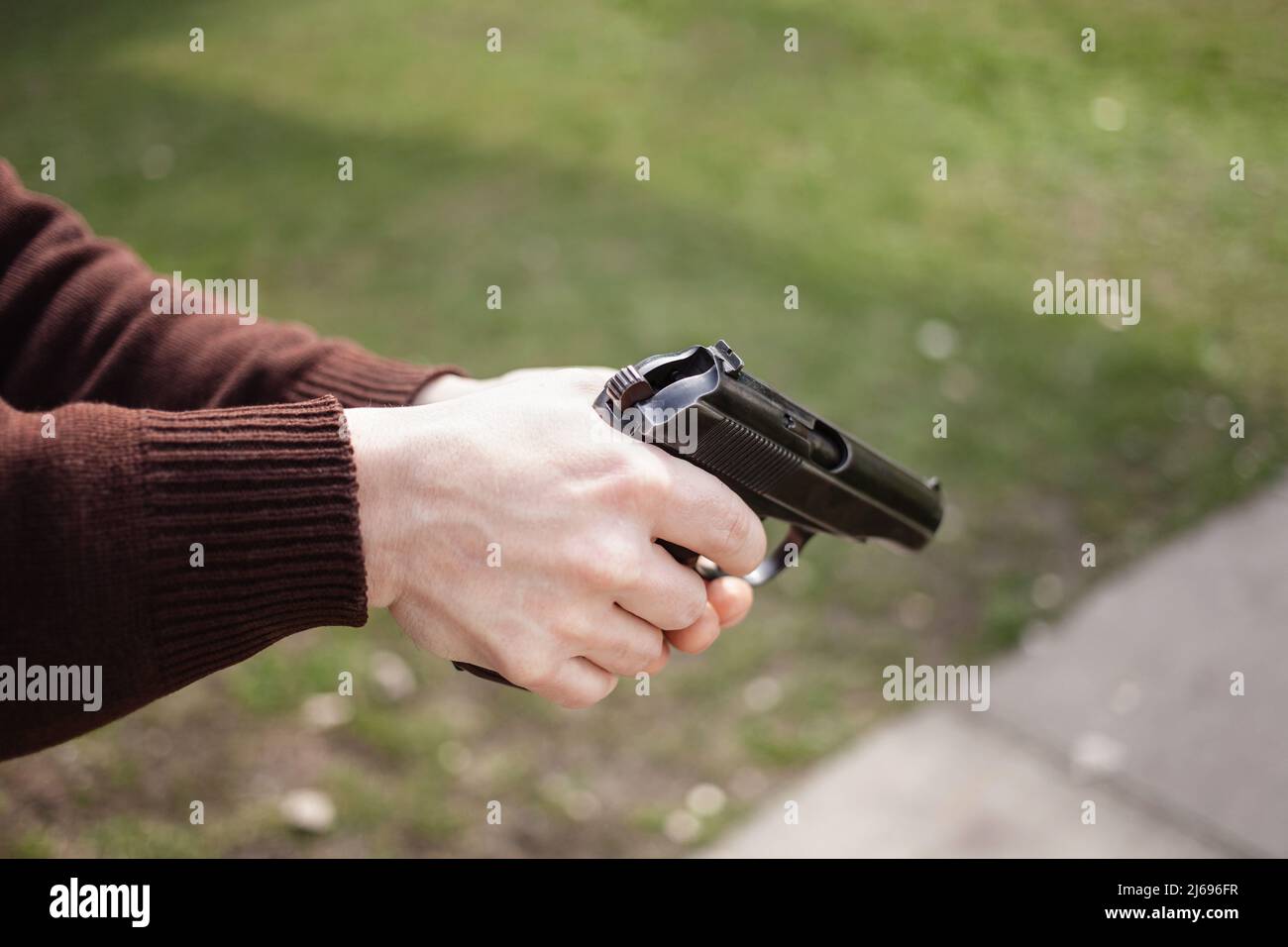 Un jeune homme charge un fusil contre une herbe verte. Armes à feu extérieur. Sport, hobbies Copy Space Banque D'Images
