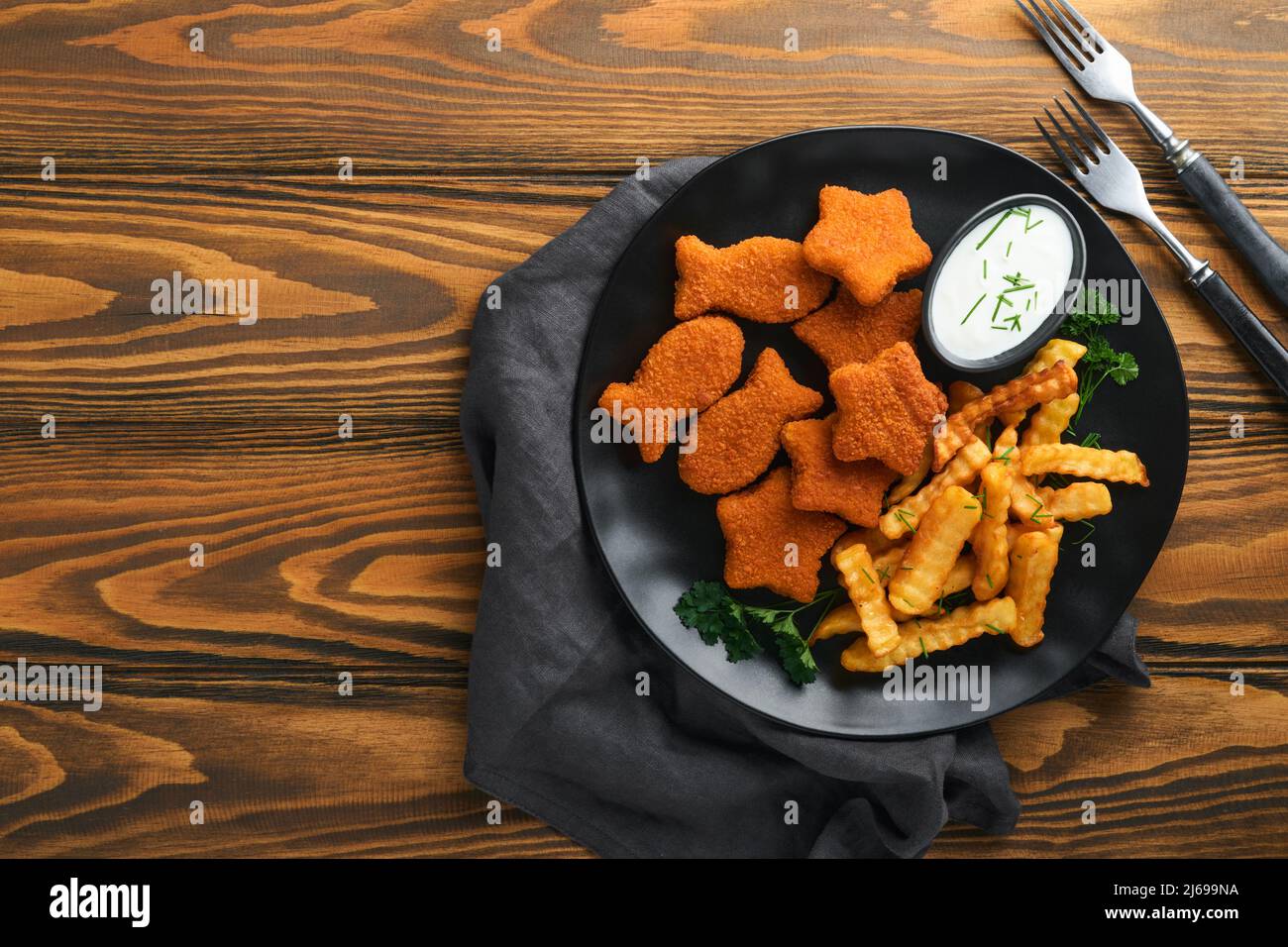 Fish and Chips, restauration rapide britannique. Bâtonnets de poisson avec frites sur plaque noire sur fond de table en bois. Plat traditionnel britannique authentique Banque D'Images