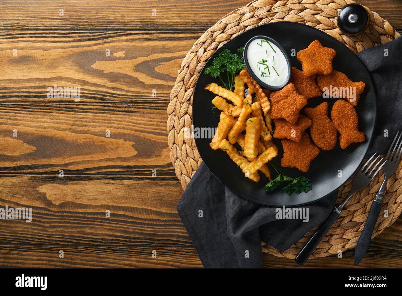 Fish and Chips, restauration rapide britannique. Bâtonnets de poisson avec frites sur plaque noire sur fond de table en bois. Plat traditionnel britannique authentique Banque D'Images