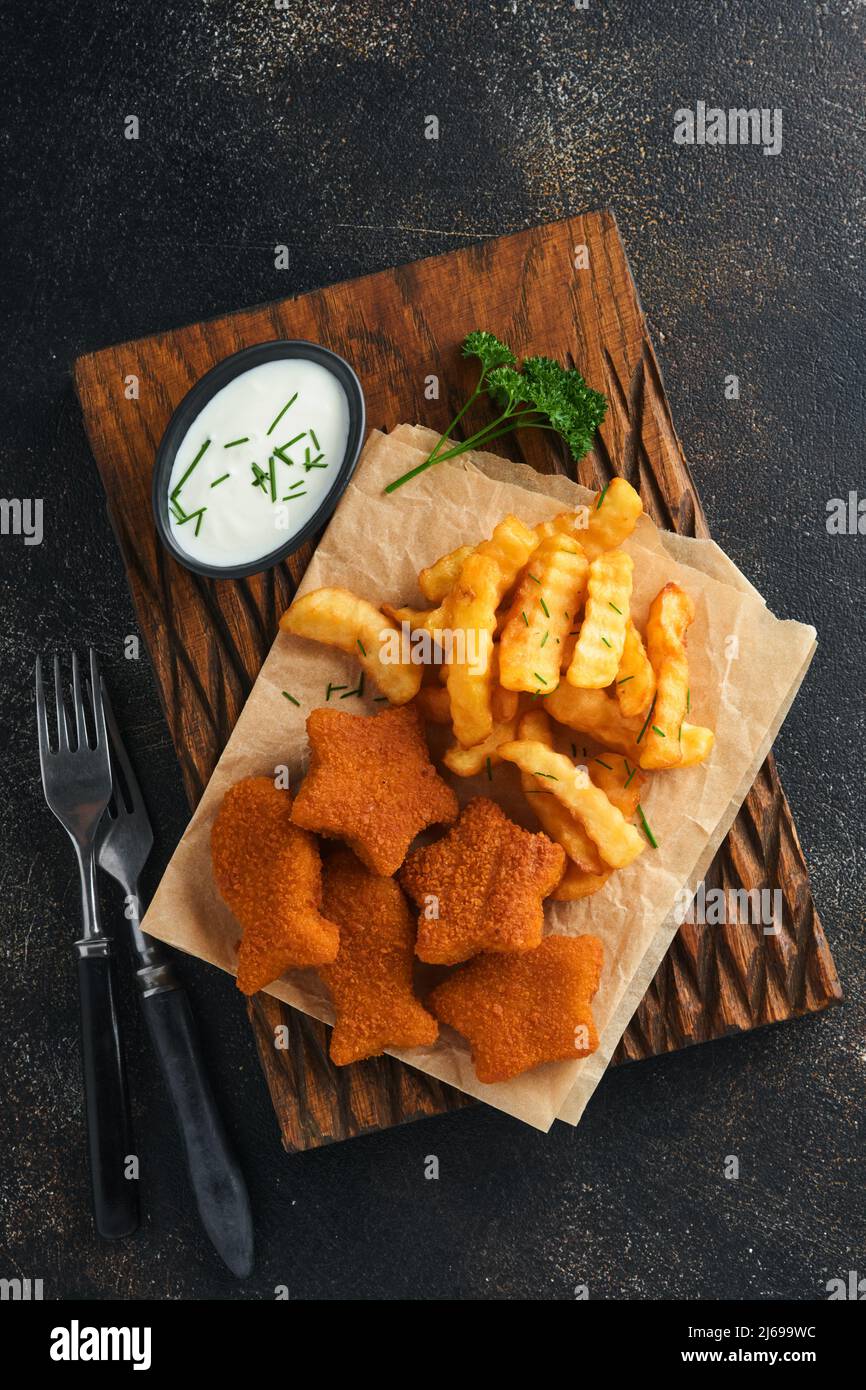Fish and Chips, restauration rapide britannique. Bâtonnets de poisson avec frites sur un panneau rustique sur fond de vieux béton foncé. Traditionnelle britannique authentique str Banque D'Images