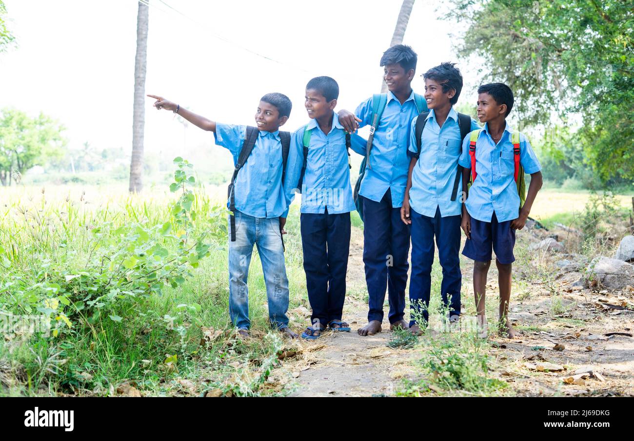 Village groupe d'enfants en uniforme avec l'utilisation de l'ordinateur portable tout en étant assis près du paddy champ - concept de l'éducation, le développement et la technologie. Banque D'Images