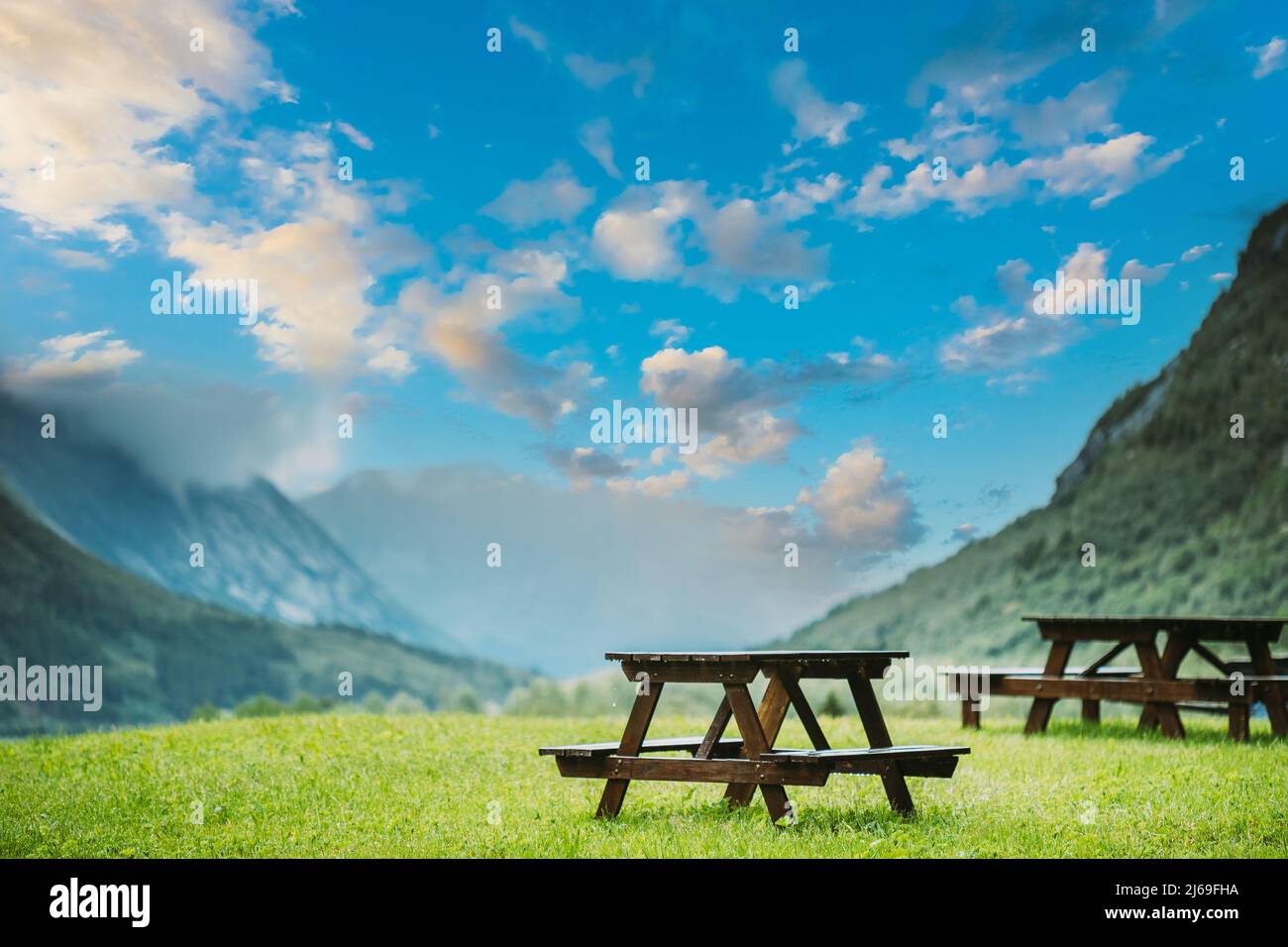 Tables et bancs en bois dans les montagnes Paysage d'été. Modifié ciel bleu calme au-dessus de la vallée Banque D'Images