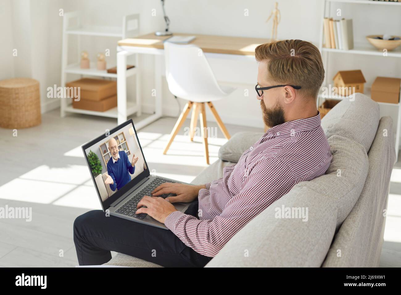 Homme d'affaires assis à la maison le week-end pour assister à une formation professionnelle ou à un webinaire en ligne sur un ordinateur portable. Banque D'Images