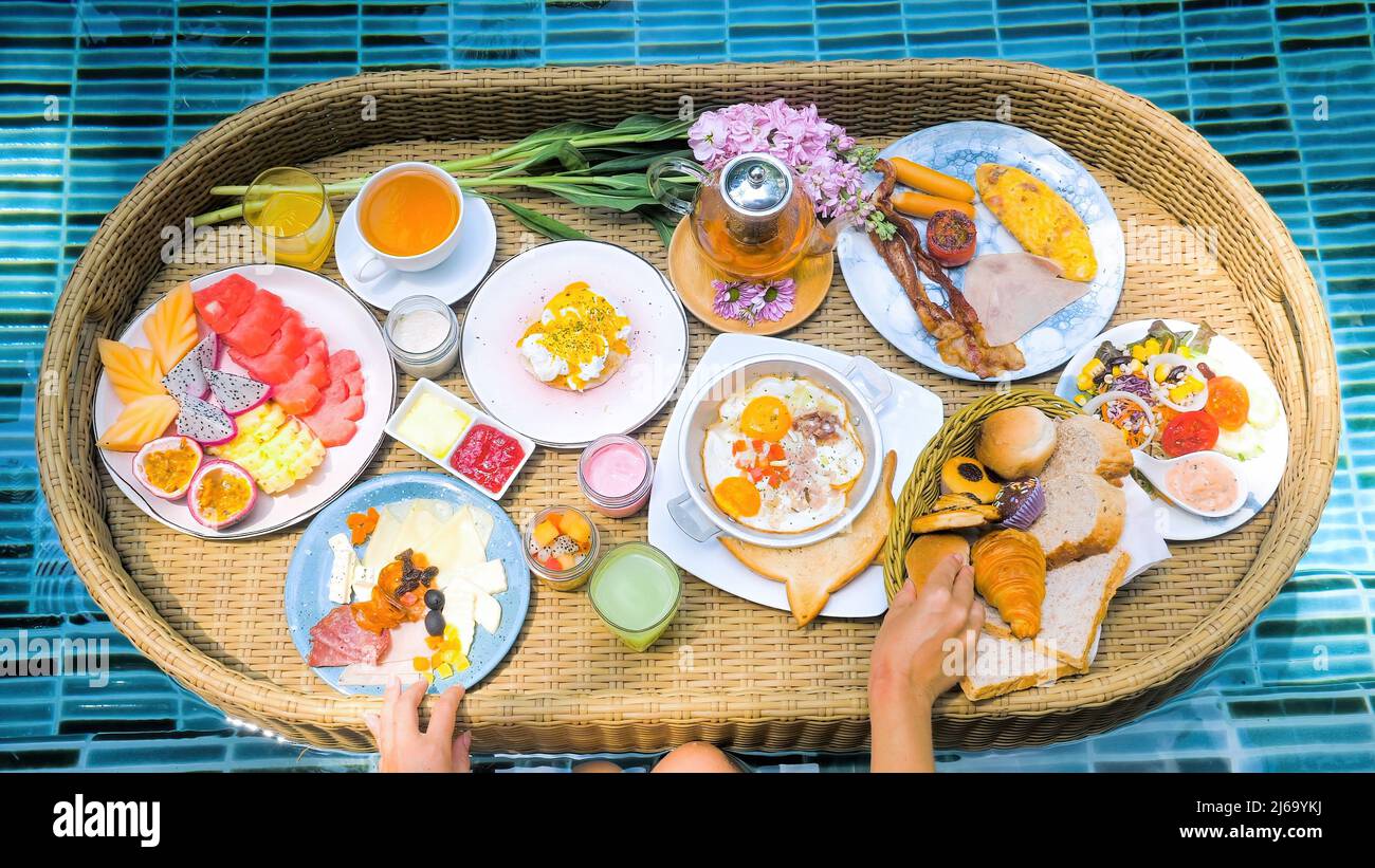 Repas colorés pour le petit déjeuner ou le déjeuner avec une femme mains sur le plateau flottant dans la piscine Banque D'Images