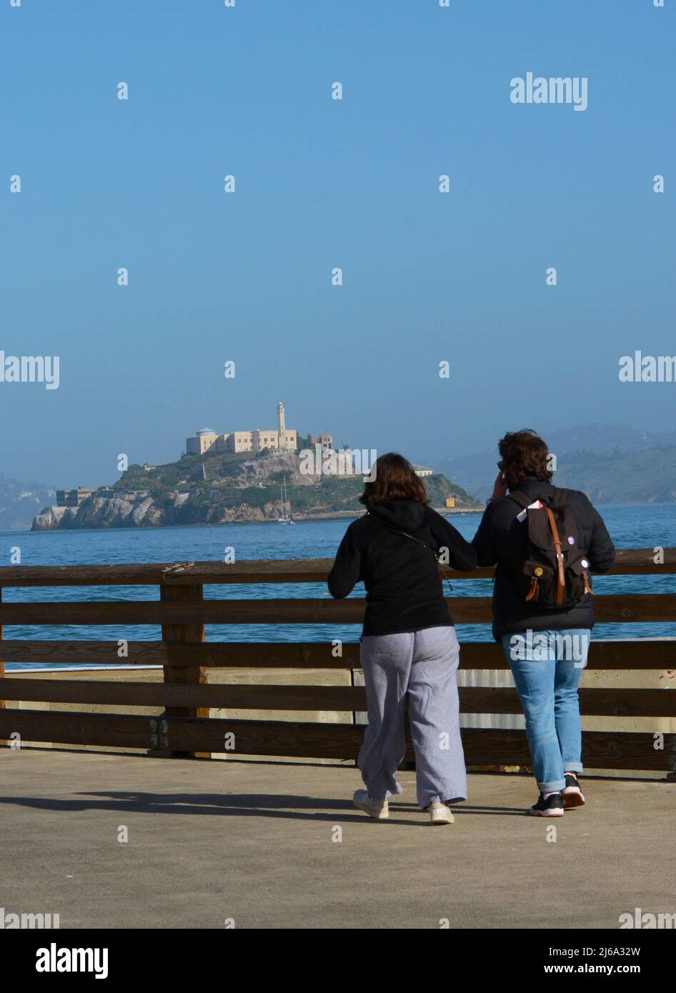 Les touristes bénéficient d'une vue sur l'île d'Alcatraz et la prison d'Alcatraz depuis un quai situé dans le quartier de Fisherman's Wharf à San Francisco, en Californie. Banque D'Images