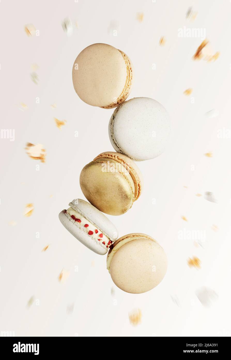 Biscuits macaron blanc, jaune, or. Petits gâteaux de macaron français colorés et sucrés. Arrière-plan beige clair flou avec des coupures de macaron cassées, des morceaux, des parties mordues. Cinq cookies au centre de la photo Banque D'Images