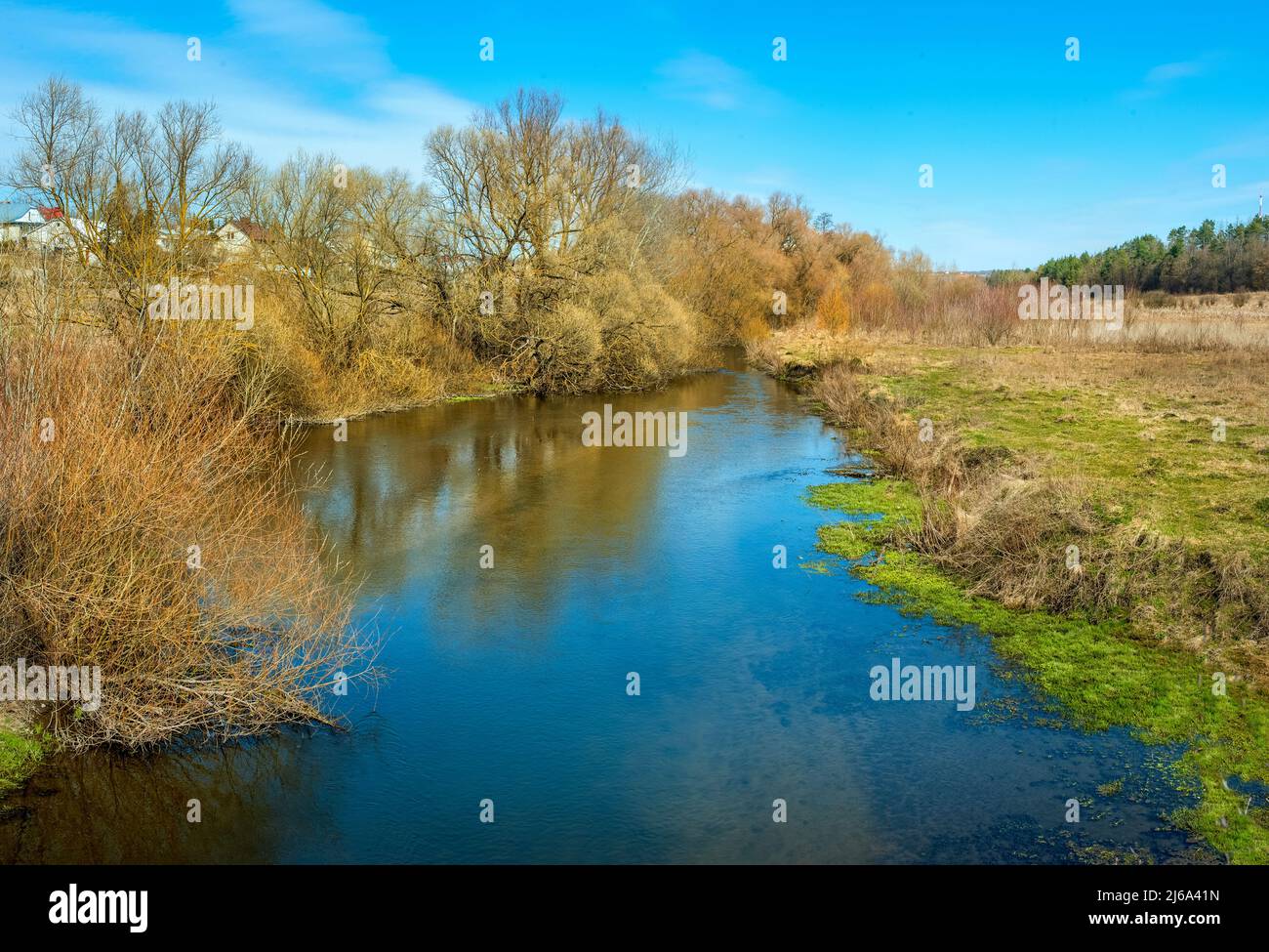 Magnifique paysage naturel de printemps coloré avec rivière bleue entourée de jeunes feuilles d'arbre en plein soleil Banque D'Images