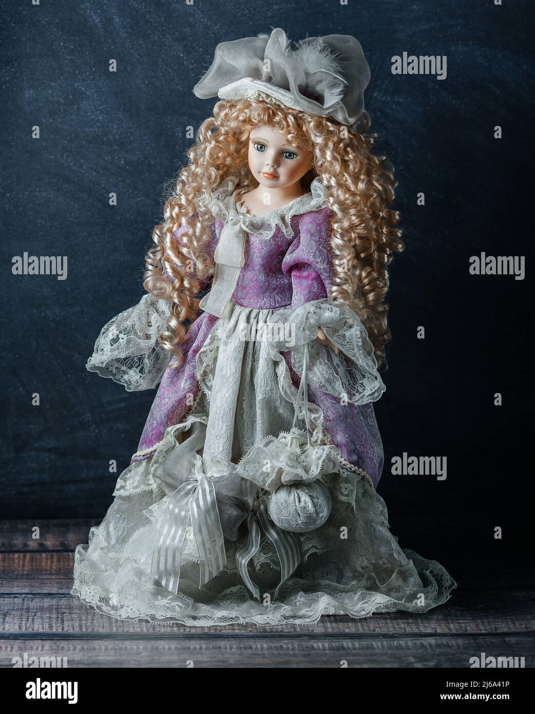 Incroyable réaliste vintage jouet avec les yeux bleus.la poupée habillée dans une robe rose et a un cheveux blond. Mise au point sélective. Poupée en porcelaine Banque D'Images