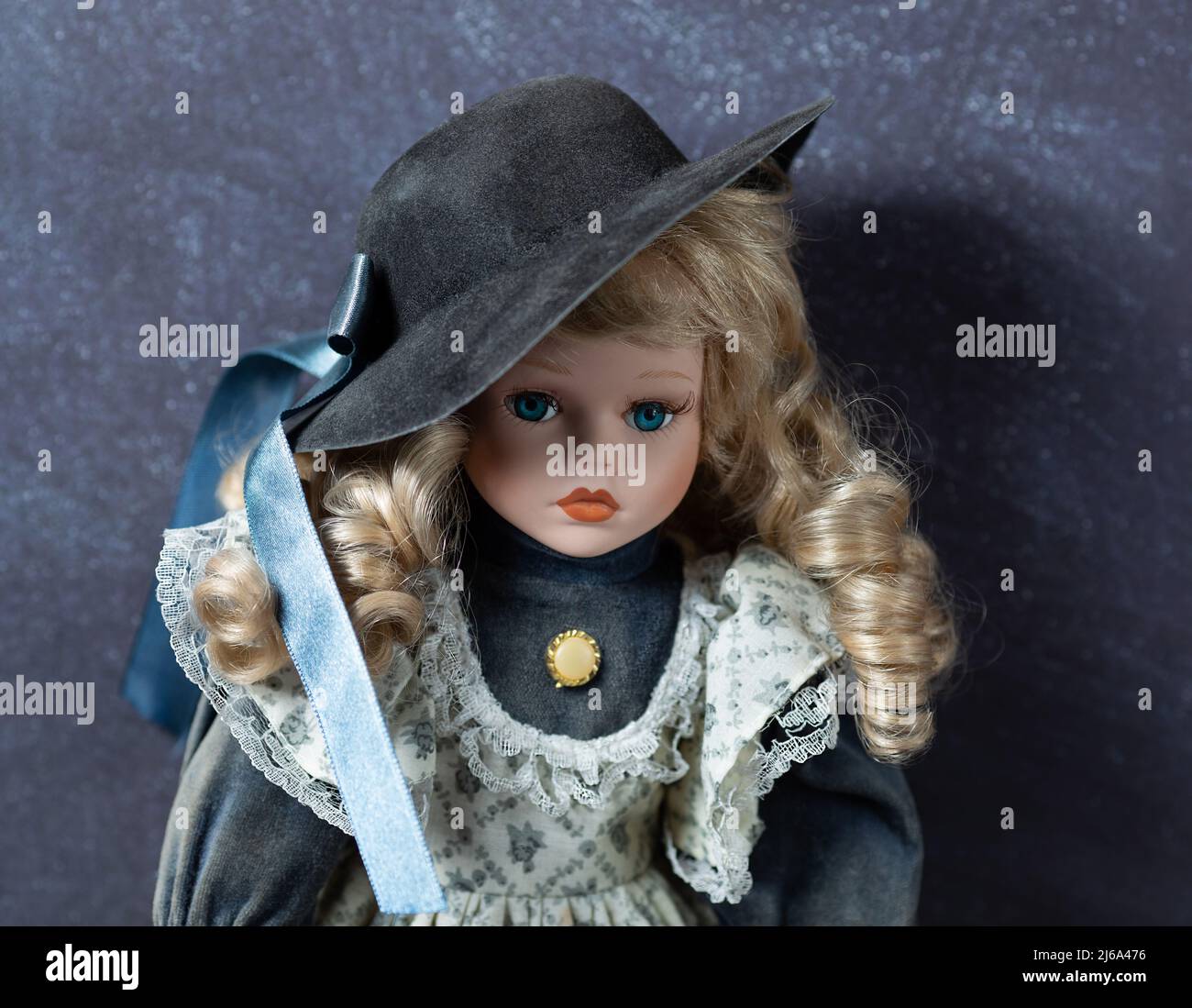 Incroyable réaliste vintage jouet avec les yeux bleus.la poupée habillée dans une robe blanc-bleu avec la dentelle et a un cheveux blond. Mise au point sélective. Poupée en porcelaine. Banque D'Images