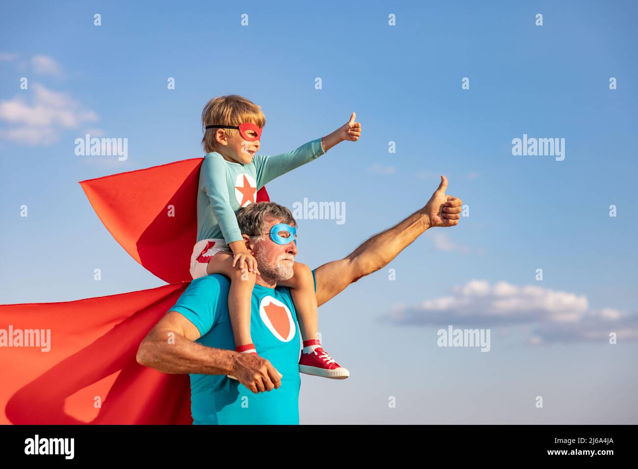 Super-héros senior homme et enfant jouant à l'extérieur. Super héros grand-père et garçon s'amusant ensemble contre fond bleu ciel d'été. Vacances en famille Banque D'Images