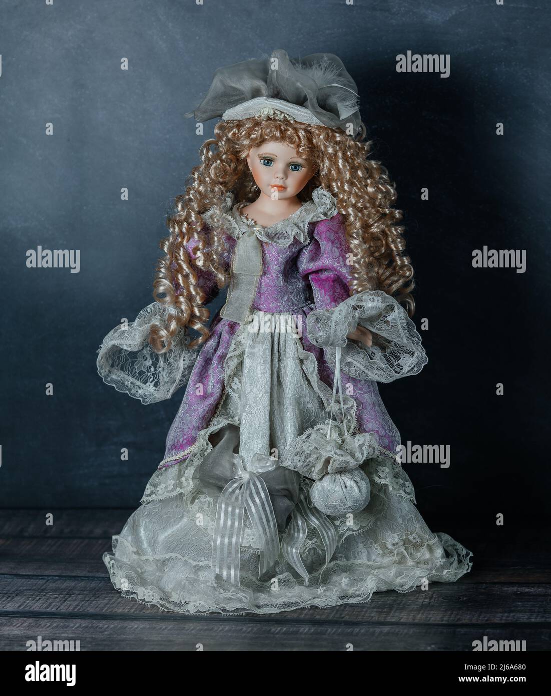 Incroyable réaliste vintage jouet avec les yeux bleus.la poupée habillée dans une robe rose et a un cheveux blond. Mise au point sélective. Poupée en porcelaine Banque D'Images