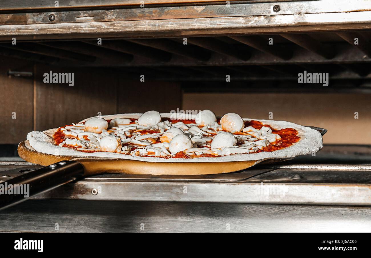 Le processus de préparation de la pizza par le chef. Pizza italienne avec jambon, fromage, mozzarella au four dans un restaurant traditionnel Banque D'Images