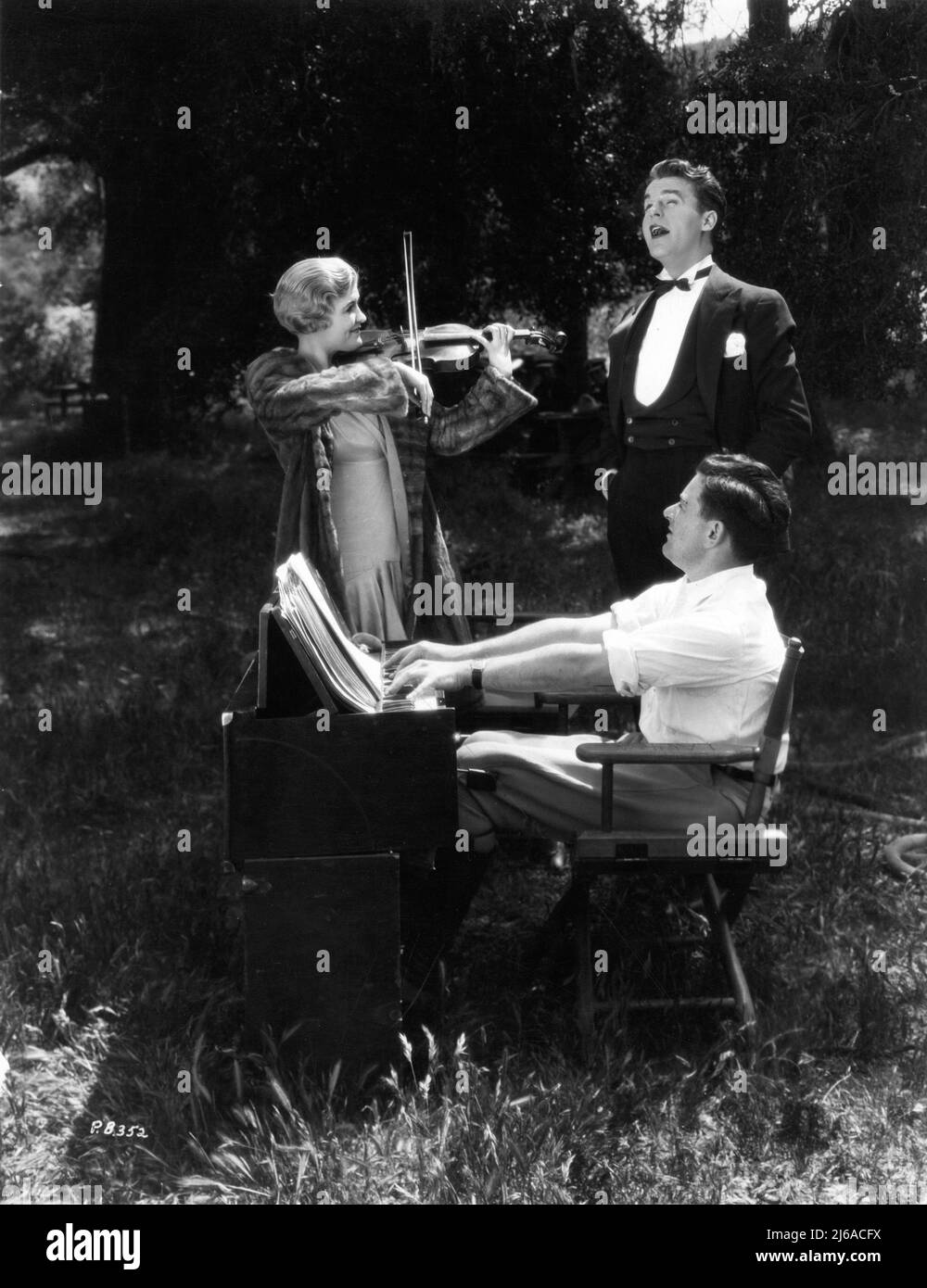 LAURA LA PLANTE NEIL HAMILTON et le réalisateur WILLIAM WYLER sur le lieu de tournage Candid faire de la musique d'ambiance pendant une pause dans le tournage du PIÈGE DE L'AMOUR 1929 réalisateur / producteur WILLIAM WYLER sorti comme Silent film et comme Silent Movie avec des séquences de conversation Universal Pictures Banque D'Images