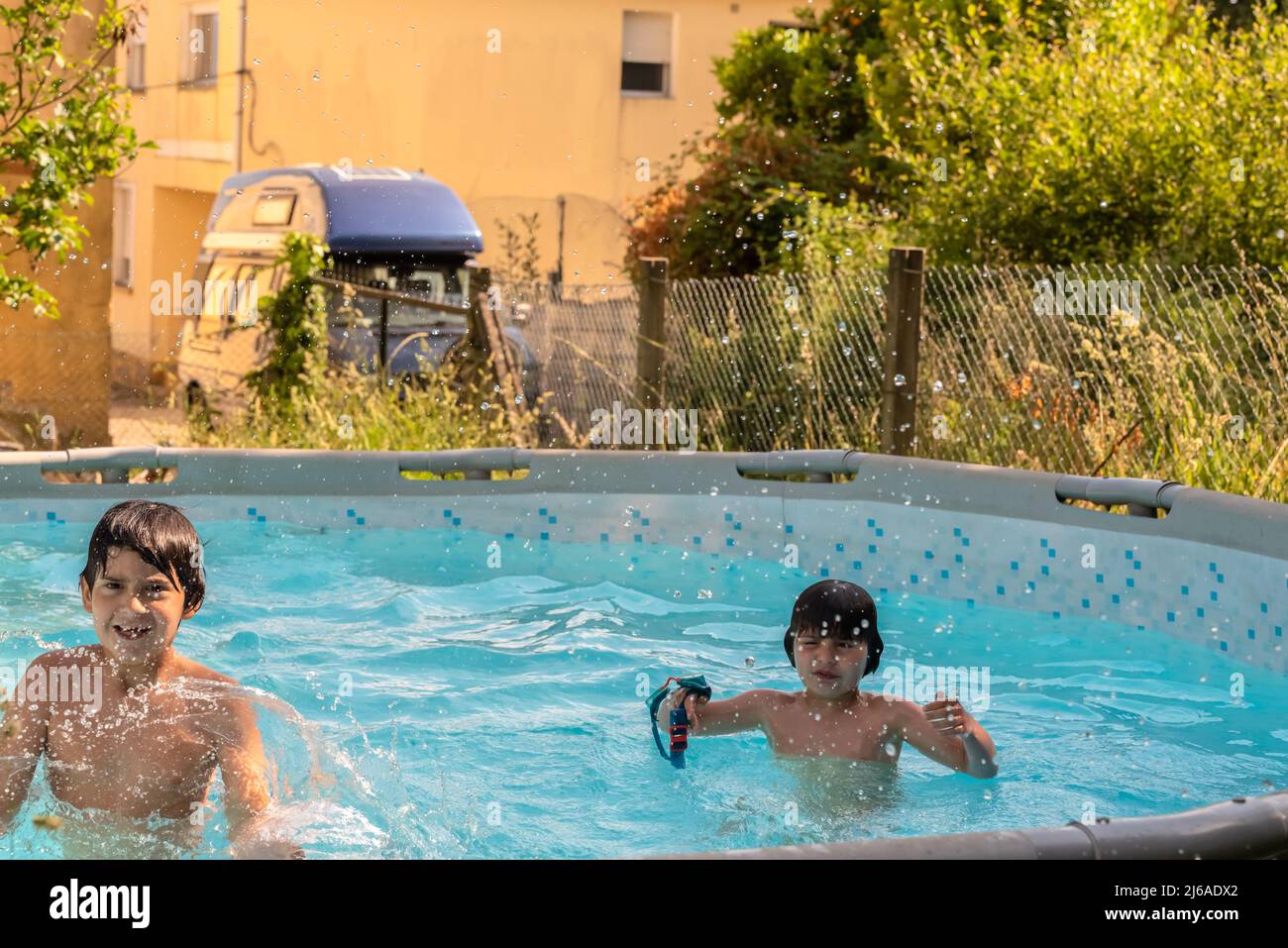 Frère et sœur caucasiens jouent barboter dans une petite piscine dans leur arrière-cour. Banque D'Images