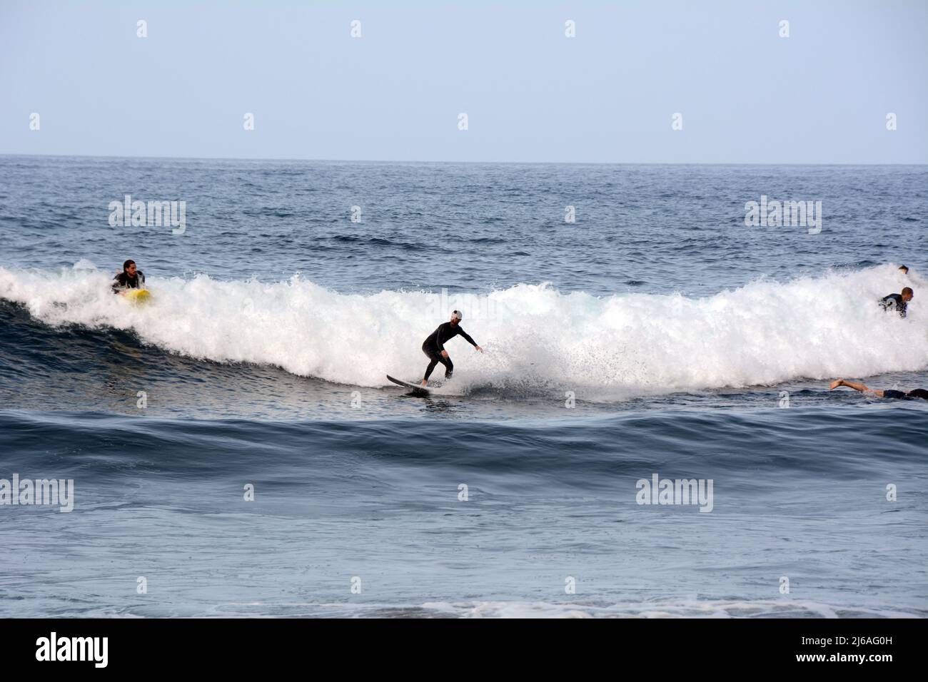 Un surfeur mâle en costume mouillé surfant sur une vague à la plage Playa del Socorro à Los Realejos, sur la côte nord de Ténérife, îles Canaries, Espagne. Banque D'Images