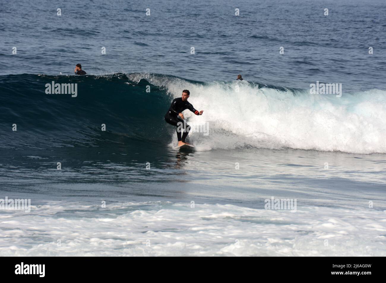 Un surfeur mâle en costume mouillé surfant sur une vague à la plage Playa del Socorro à Los Realejos, sur la côte nord de Ténérife, îles Canaries, Espagne. Banque D'Images