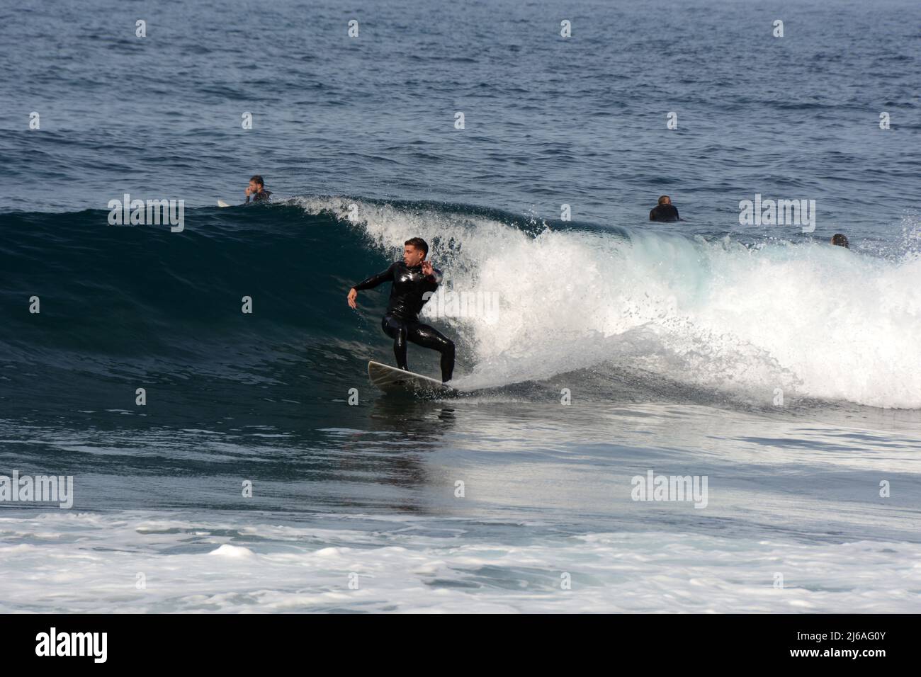 Un surfeur mâle en costume mouillé surfant sur une vague à la plage Playa del Socorro à Los Realejos, sur la côte nord de Ténérife, îles Canaries, Espagne. Banque D'Images