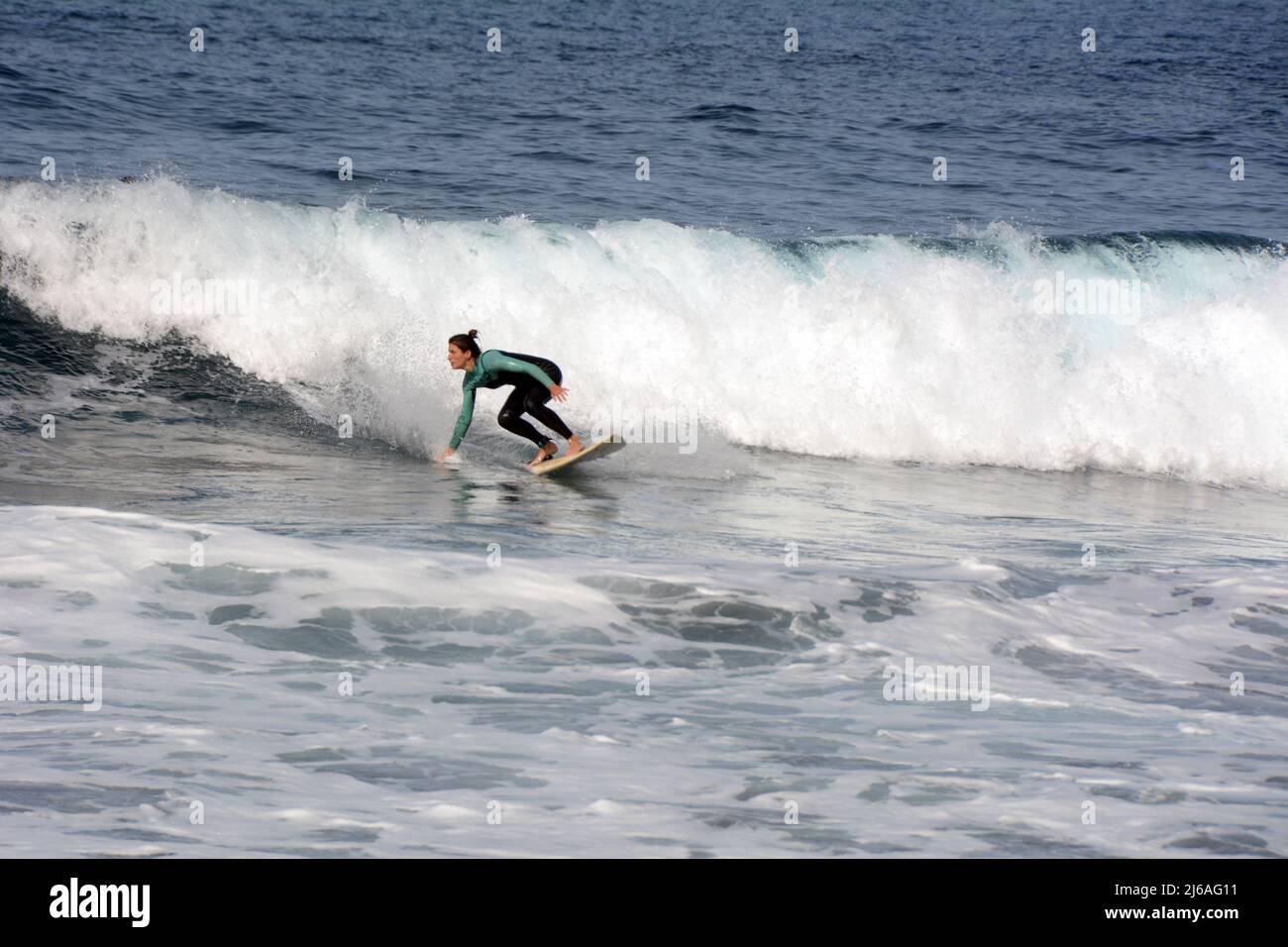 Une femme surfeuse en costume mouillé surfant sur une vague à la plage Playa del Socorro à Los Realejos, sur la côte nord de Ténérife, îles Canaries, Espagne. Banque D'Images