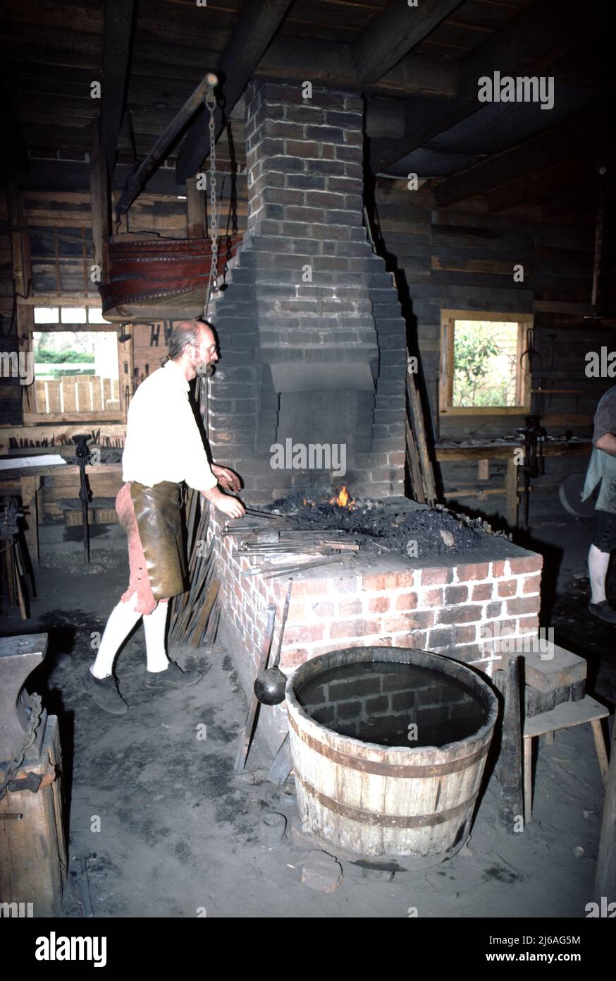 Williamsburg, Virginie. ÉTATS-UNIS 9/1987. Maîtrisez les forgerons de Colonial Williamsburg. Ces smiths font l'artisanat des fixations métalliques utilisées par d'autres artisans de la ville coloniale de Williamsburg, tels que les roues droites, les accessoires de maison tels que les clous, les charnières et les loquets; et, les sangles de seau et de baril Cooper, ainsi que l'équipement agricole et la réparation. Banque D'Images