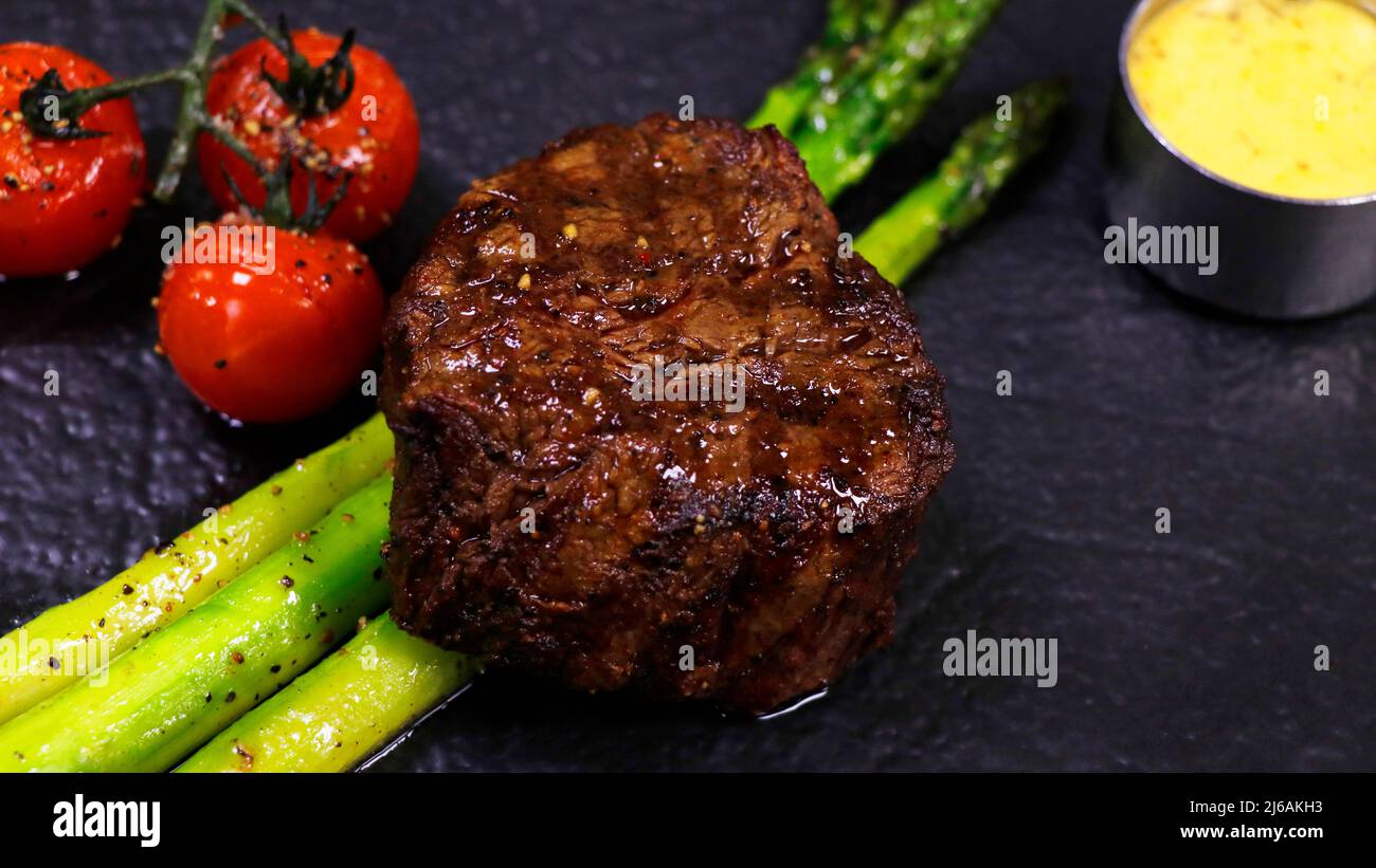 filet de filet de bœuf grillé avec asperges, sauce tomate et hollandaise dans une assiette Banque D'Images