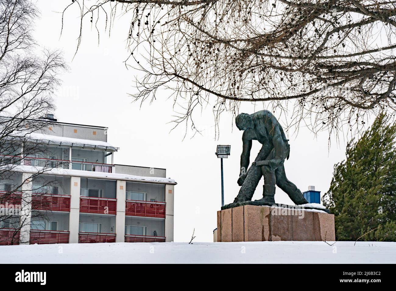 Rovaniemi, Finlande - 18th mars 2022 : statue en bronze d'un bûcheron écornant une bûche, par une journée enneigée à Rovaniemi, Finlande. Banque D'Images