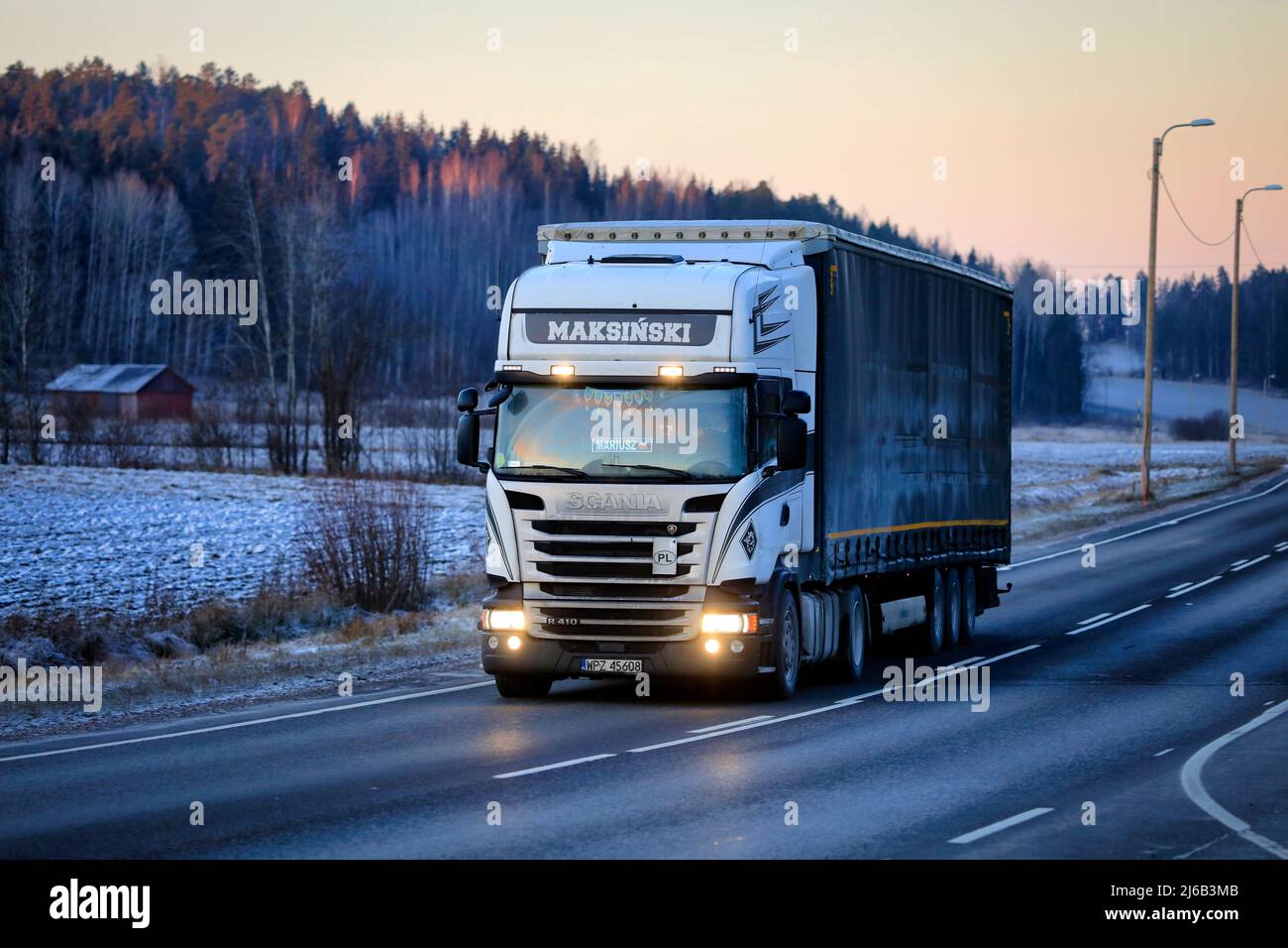 Le camion semi-remorque Scania R410 Maksinski sur la route pendant une belle soirée d'hiver, feux de route brièvement allumés. Salo, Finlande. 22 décembre 2021. Banque D'Images