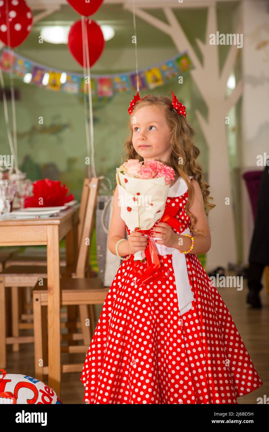 Joyeux enfant fille célébrant la fête d'anniversaire avec bouquet de fleurs dans le café. Nom de l'enfant-jour. Banque D'Images