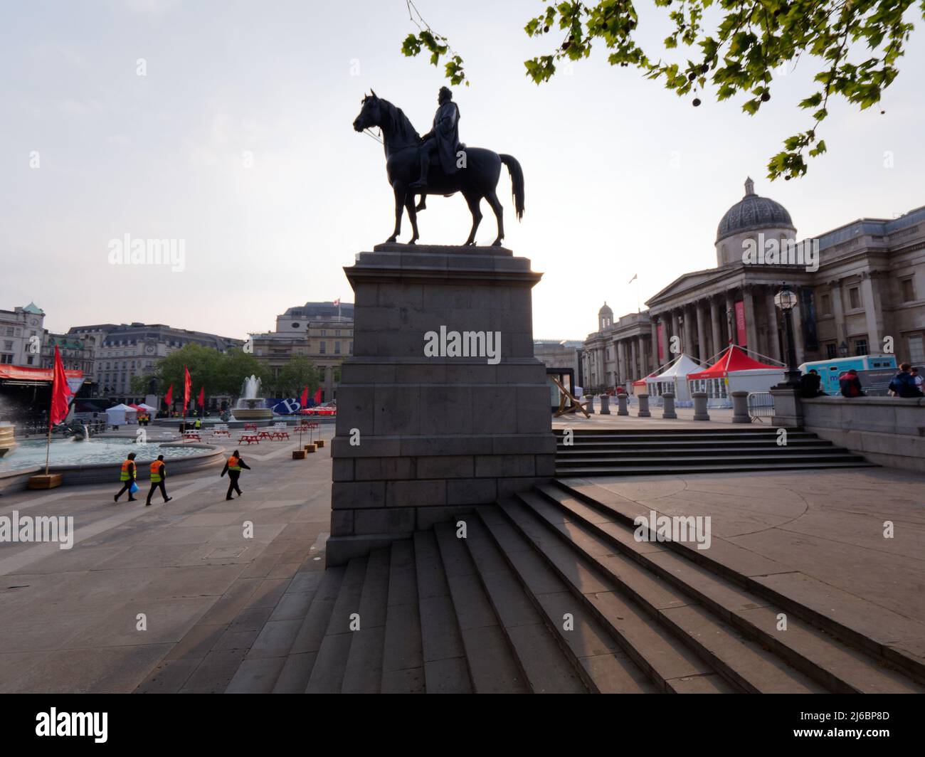 Trois officiels marchent sur Trafalgar Square après que les célébrations de la journée de Saint-Georges aient terminé avec le centre de la statue équestre. Banque D'Images