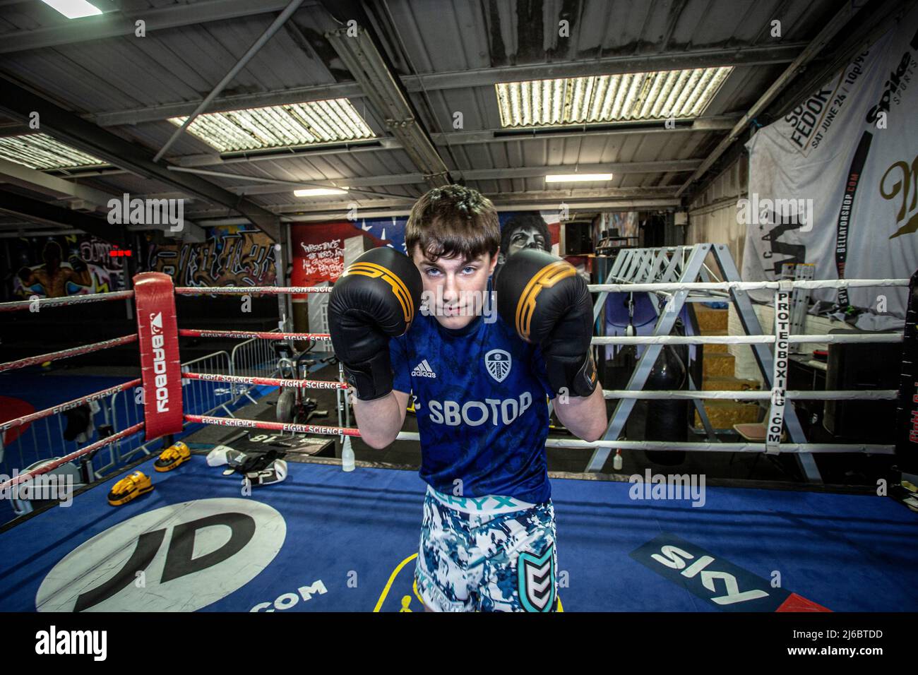 Un jeune boxeur masculin pose sur un banc de boxe dans un gymnase local du West Yorkshire, en Angleterre. Banque D'Images