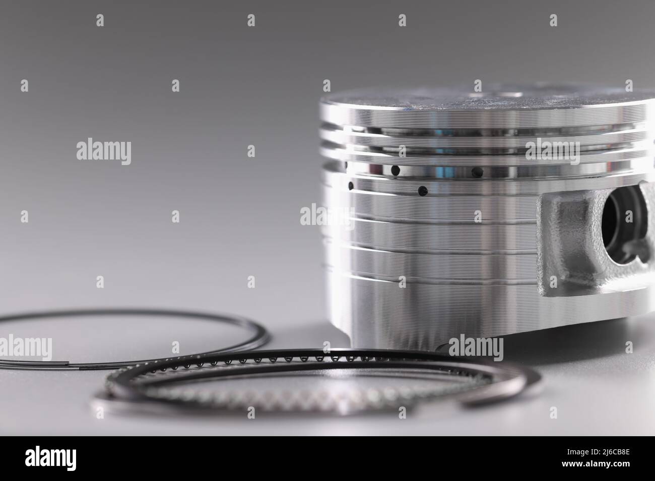 Gros plan de la pince et des segments de piston, moteur à combustion interne sur fond gris. Détails de la voiture, transport, concept de composant Banque D'Images