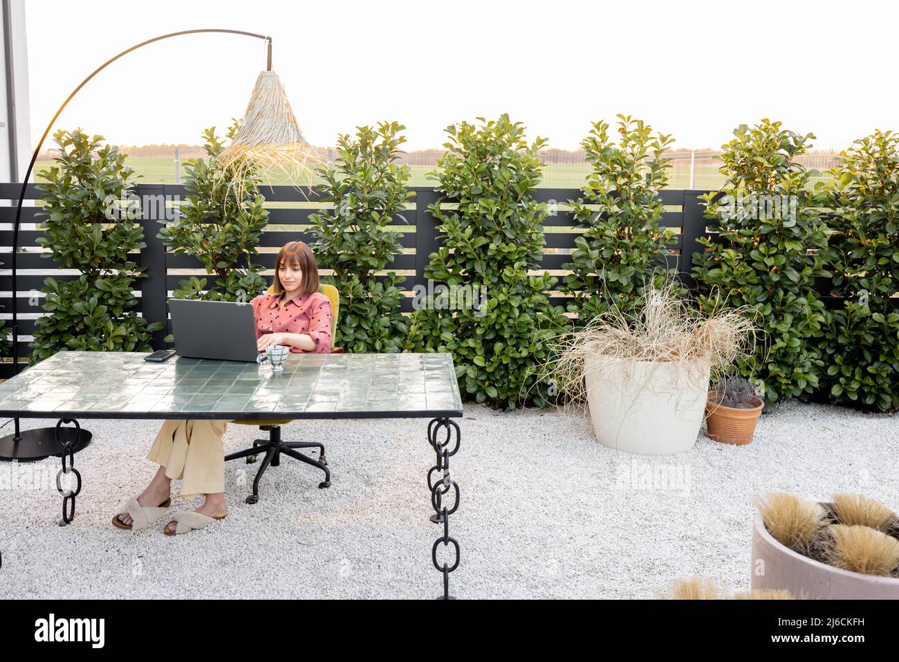 Femme travaille sur ordinateur portable en ligne dans le jardin à l'extérieur Banque D'Images