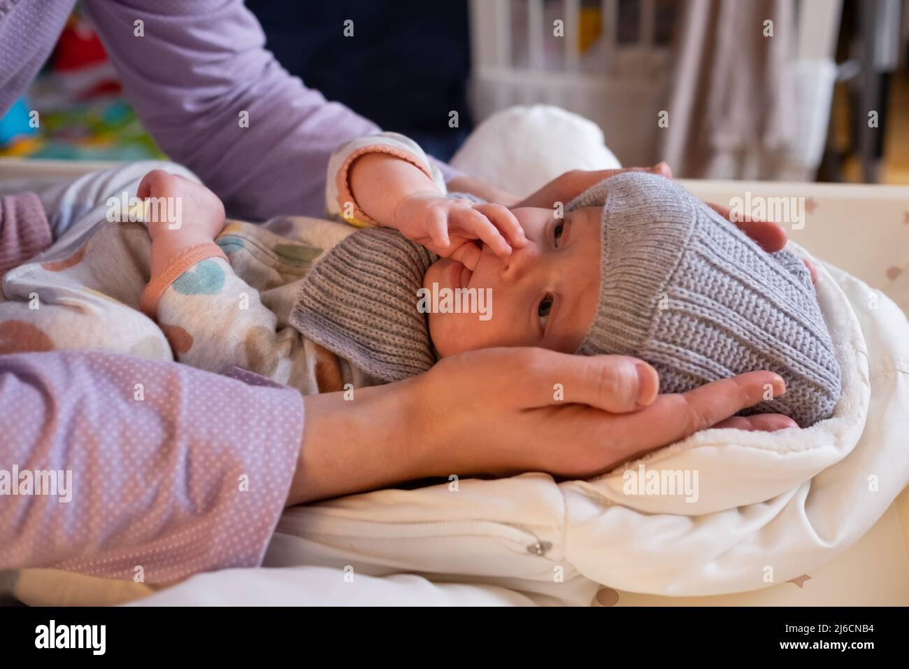 Une femme mere met une veste chaude pour un bebe garcon. Maman habille un enfant dans des vetements d hiver sur le lit Photo Stock Alamy