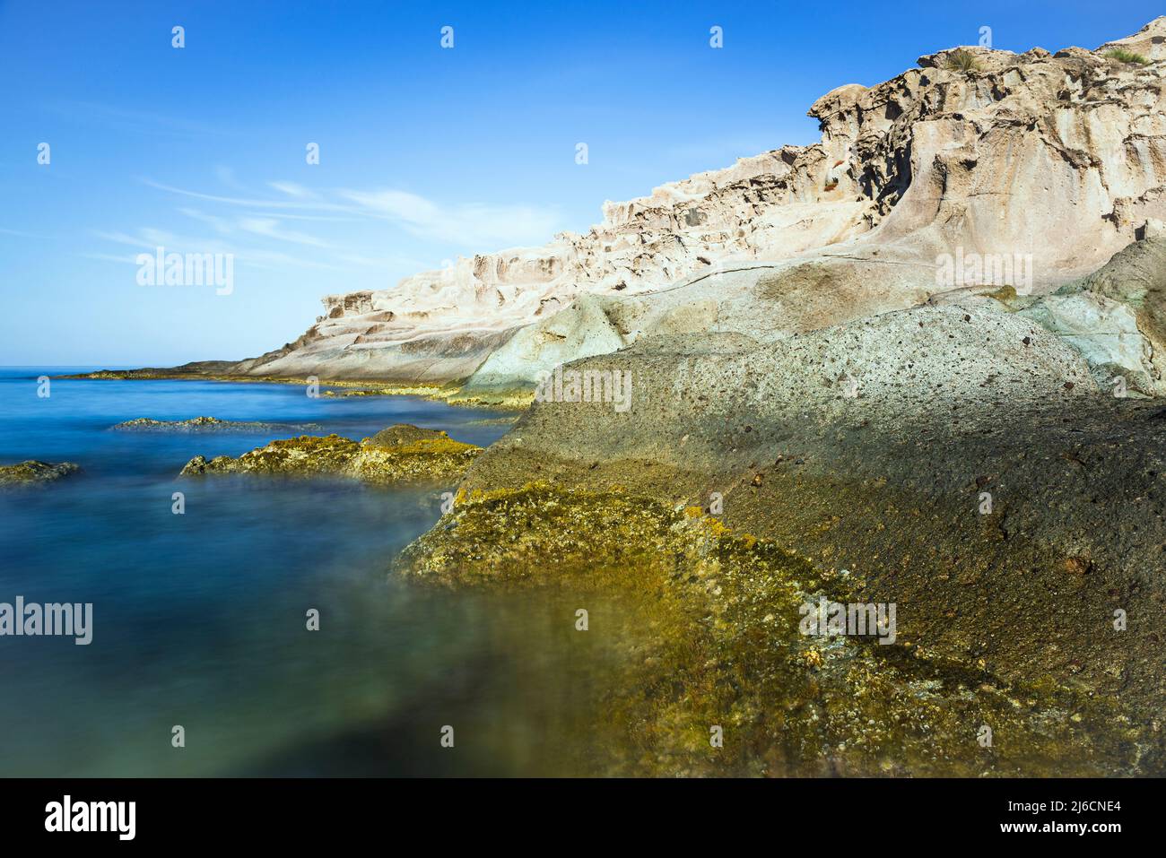 Beauté naturelle méditerranéenne - formations rocheuses dentelées et colorées dans les vagues de la mer Méditerranée bleu profond sur la côte ouest de la Sardaigne, Italie Banque D'Images