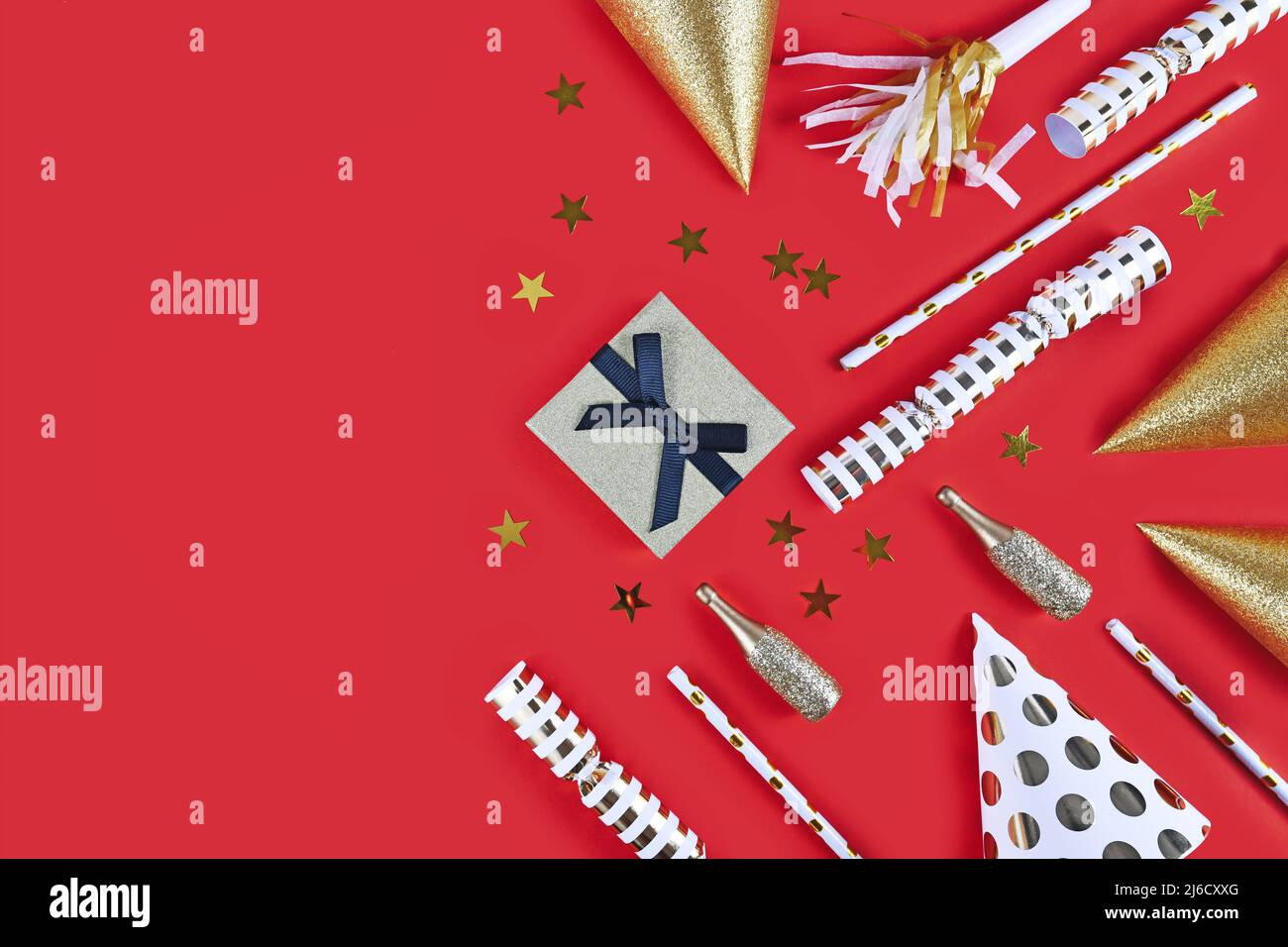 Chapeaux de fête d'or, petites bouteilles de champagne, confettis d'étoiles et cadeau sur fond rouge Banque D'Images Chapeaux de fête d'or, petites bouteilles de champagne, confettis d'étoiles et cadeau sur fond rouge Banque D'Images