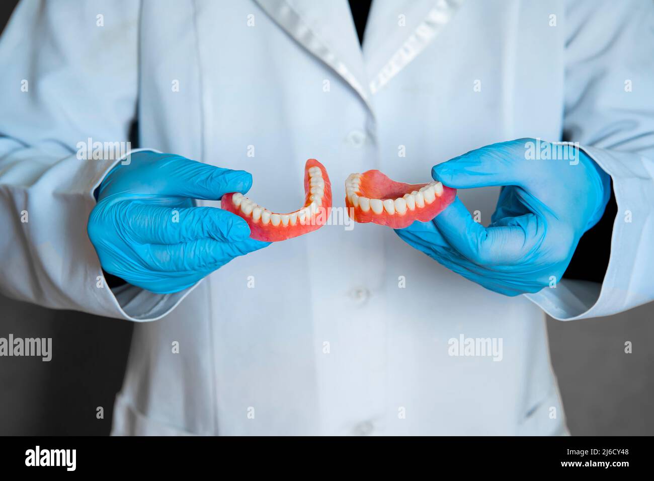 Prothèse dentaire dans les mains du médecin en gros plan.Dentiste tenant un pont dentaire en céramique.Vue avant de la prothèse complète.Pho conceptuel de la dentisterie Banque D'Images