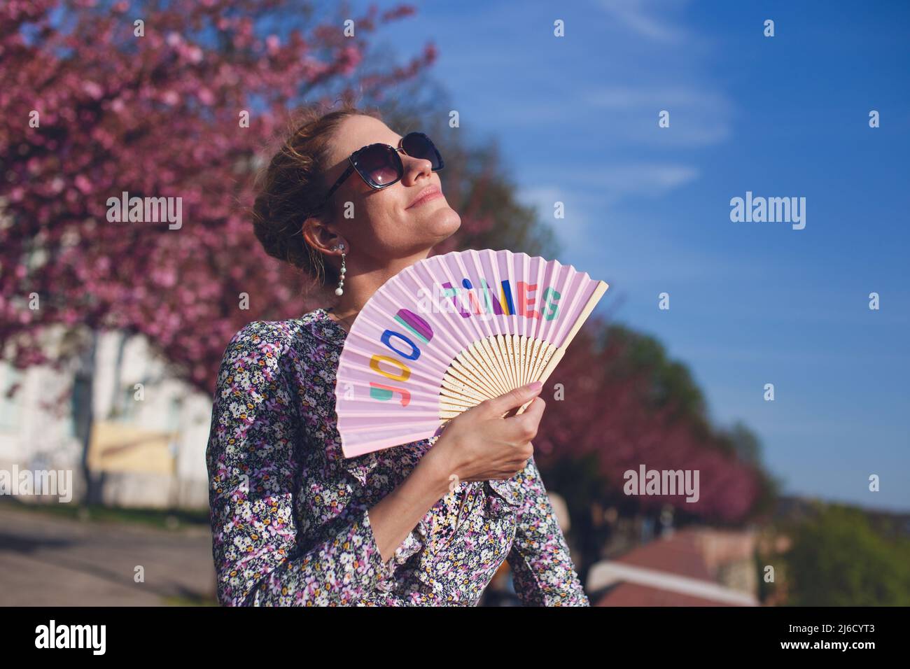 Femme nostalgique tenant le fan de la main de Good Times au coucher du soleil pendant le printemps Banque D'Images