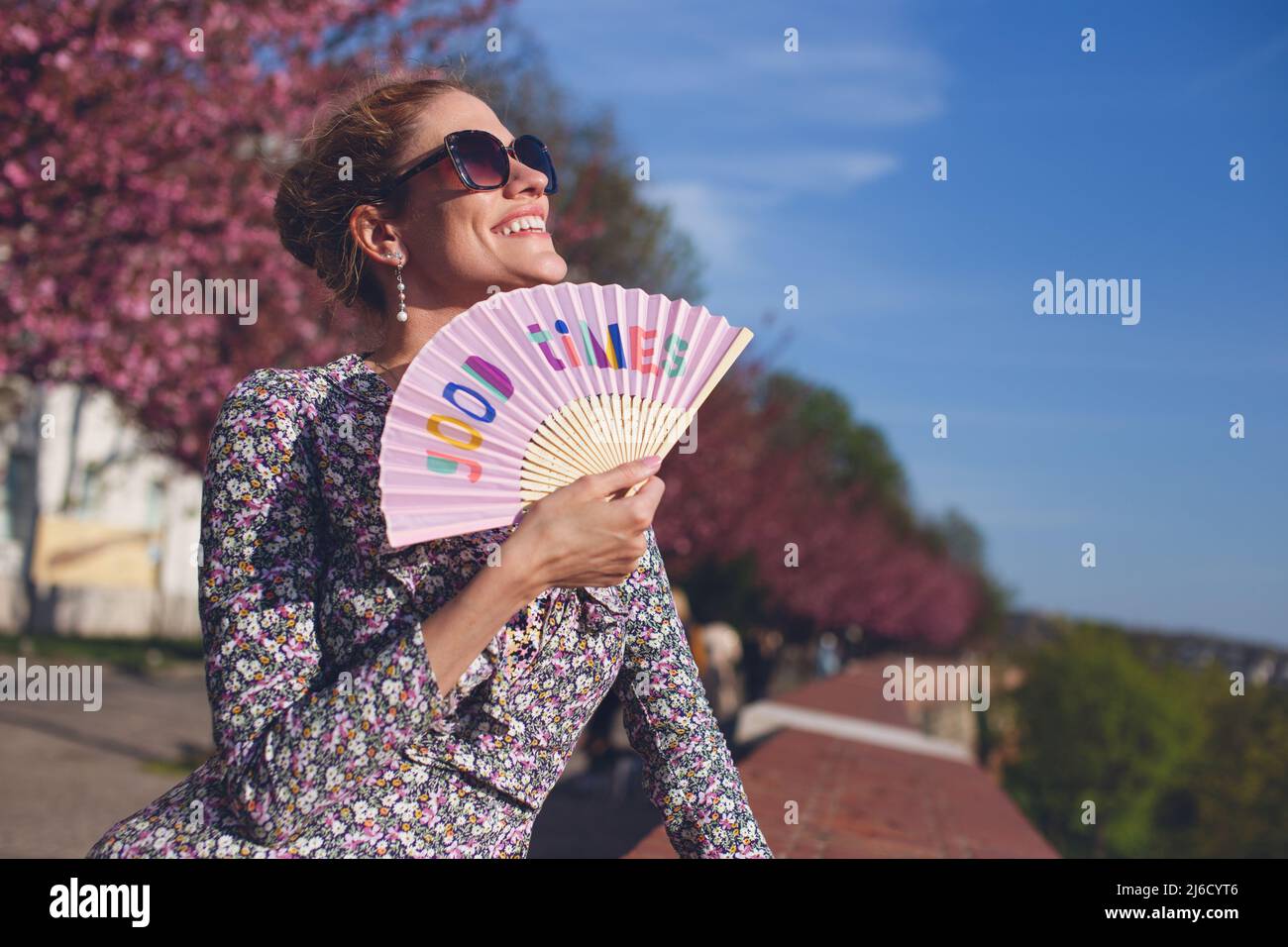 Femme nostalgique tenant les bons temps ventilateur de main au coucher du soleil pendant le printemps, sourire torothy Banque D'Images