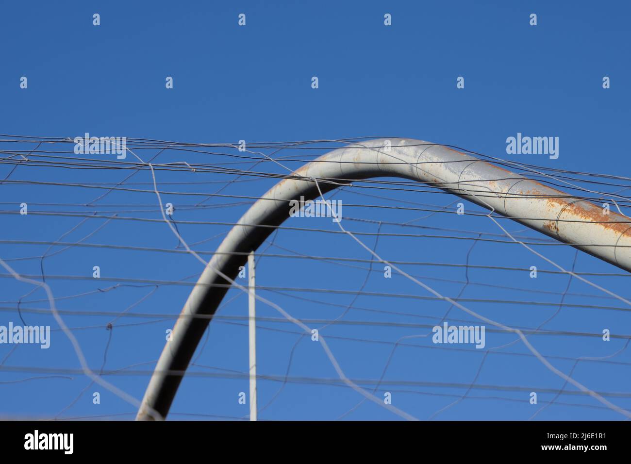 Arc métallique d'une serre avec maillage métallique contre le ciel bleu Banque D'Images