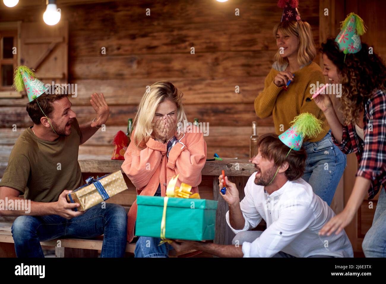 Une jeune fille fête son anniversaire avec ses amis au porche du chalet lors d'une belle journée. Vacances, nature, chalet, célébration Banque D'Images