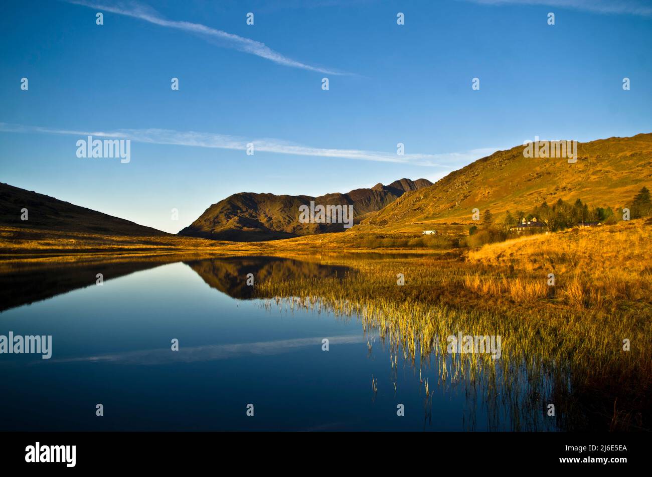 Réflexions dans un lac de Snowdonia avec la lumière du matin qui attrape la chaîne à l'arrière qui mène à Mt Snowdon, pays de Galles, Royaume-Uni Banque D'Images